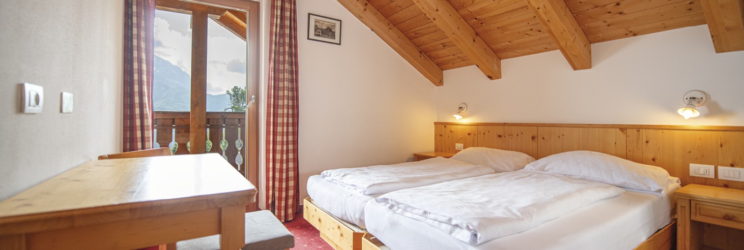 Rifugio Molignon Alpe di Siusi | Massimo benessere: le nostre camere per un sonno da sogno La foto mostra la camera da letto con letto matrimoniale, scrivania e balcone.