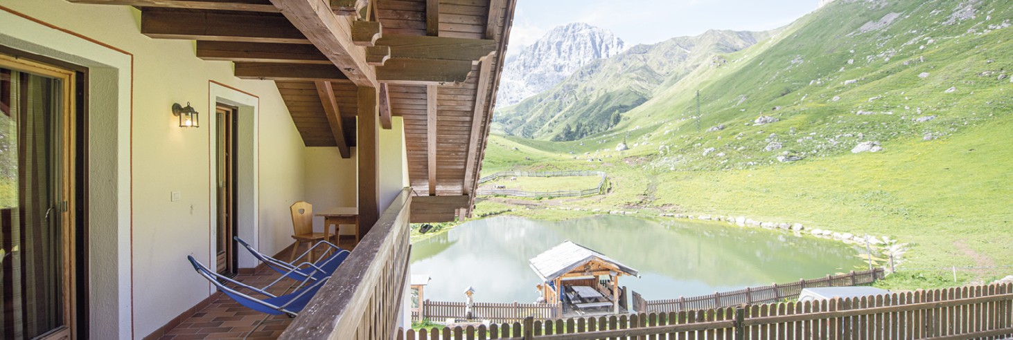 Rifugio Molignon Alpe di Siusi | Relax e tranquillità nel cuore delle Dolomiti La foto mostra la vista dal balcone. Si può vedere il lago e la natura circostante e le montagne.