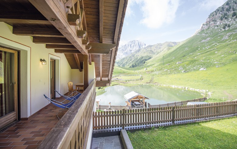 La foto mostra la vista dal balcone. Si può vedere il lago e la natura circostante e le montagne.