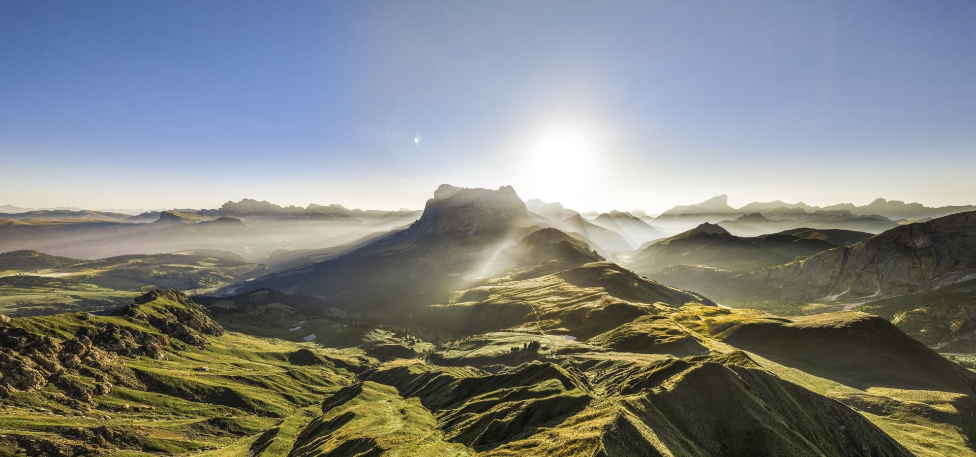 Molignonhütte Seiser Alm | Panoramic view of the Langkofel and Plattkofel: Unique impressions of the Seiser Alm The picture shows a drone shot of the Sassolungo and Sassopiatto. It shows the green meadows of the Seiser Alm.