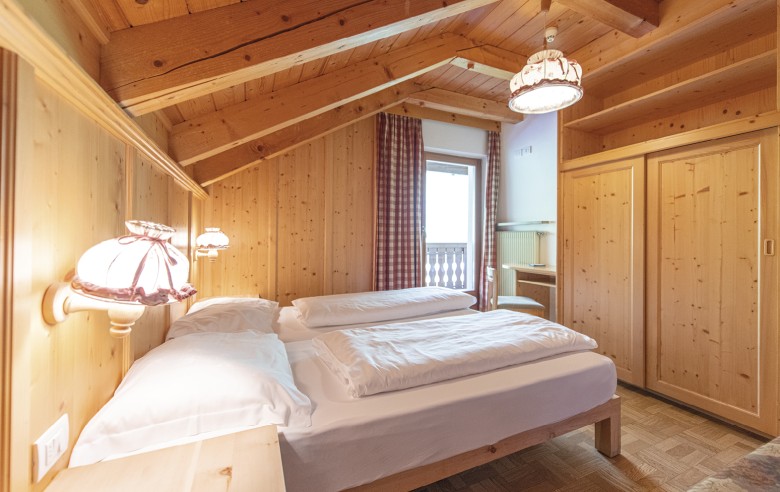 La foto mostra il letto matrimoniale, un armadio e il balcone con vista sulle Dolomiti circostanti.