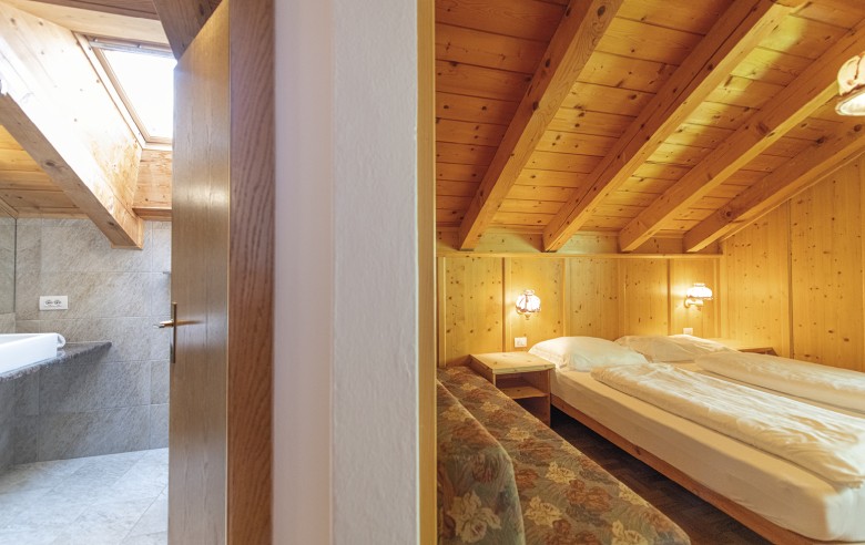 La foto mostra una metà il bagno e l'altra metà la camera da letto. Il bagno è modernamente attrezzato con grandi flussi. La camera da letto mostra il letto matrimoniale e un divano.