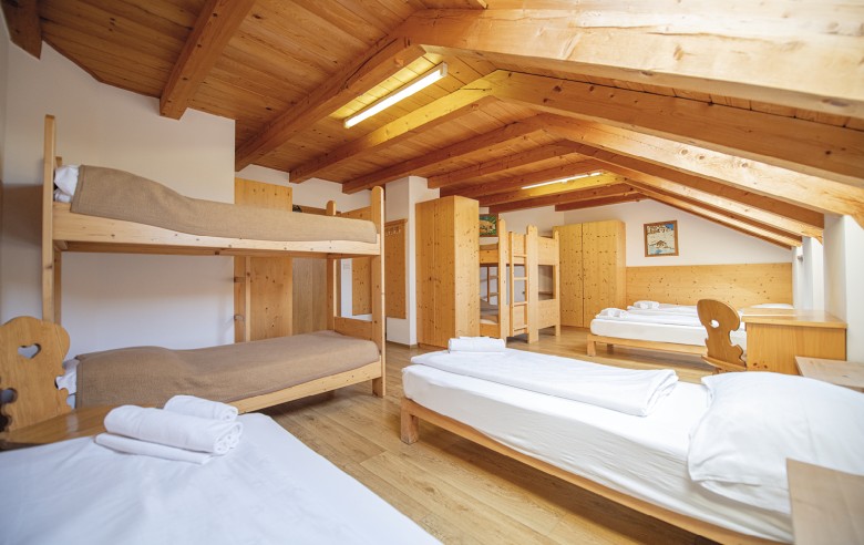 La foto mostra il materasso. Si possono vedere letti singoli e a castello, così come un armadio e diverse scrivanie.