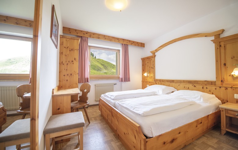 La foto mostra una camera matrimoniale con armadio e scrivania. La camera è modernamente arredata con vista sulla natura.