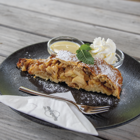 Rifugio Molignon Alpe di Siusi | Regionale, fresco, gustoso: il nostro cibo di rifugio vizia le vostre papille gustative L'immagine mostra uno strudel di mele con panna e salsa alla vaniglia.