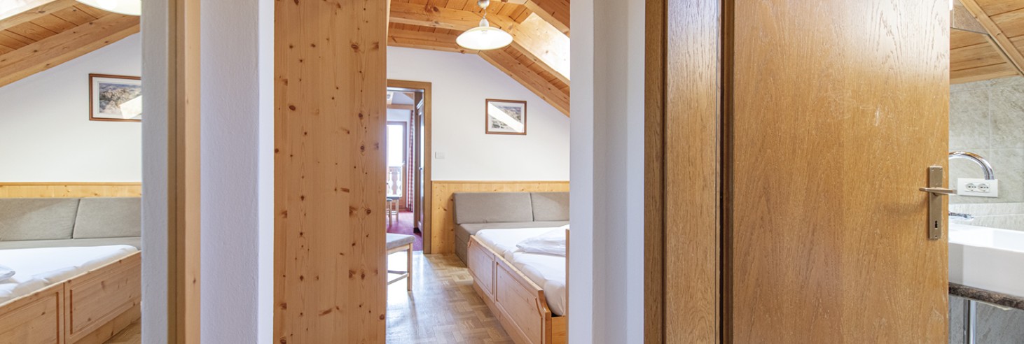 Rifugio Molignon Alpe di Siusi | La vostra casa in montagna: camere accoglienti per tutte le esigenze La foto mostra una parte della camera da letto e del bagno. Si può vedere che entrambi sono arredati molto moderno e accogliente.