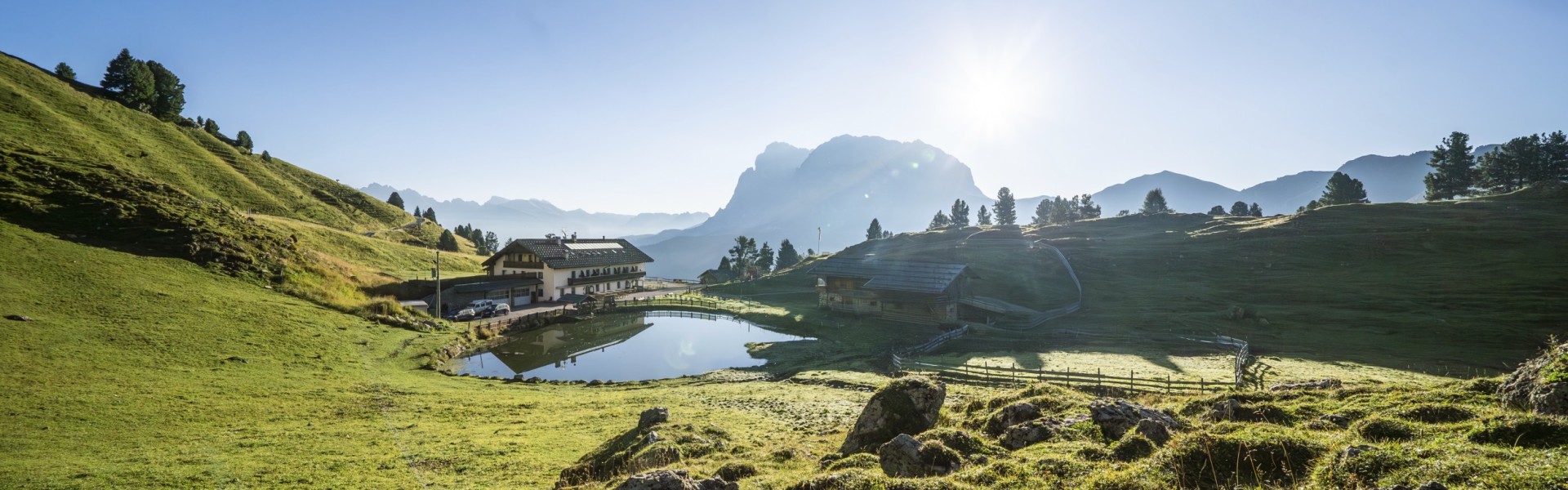 L'immagine mostra un'immagine aerea del rifugio Molignon in estate. Si può vedere il bacino lungo e piatto e il lago.